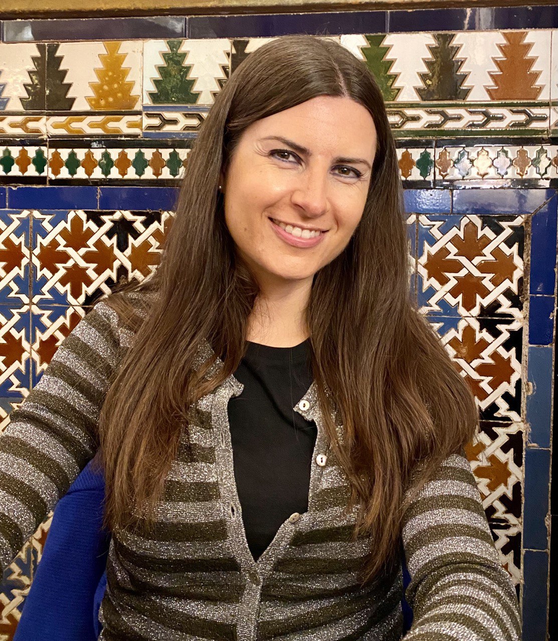 Chiara sorride davanti a una parete di azulejos blu, verdi e ocra